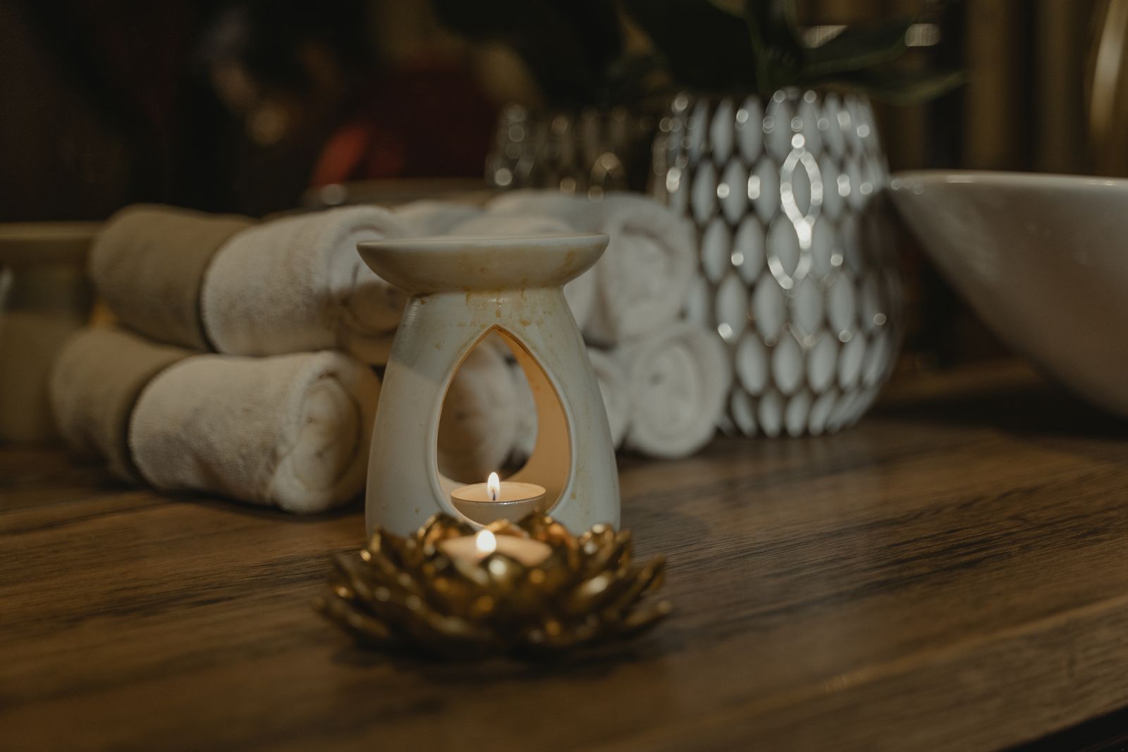 Inside the Moroccan Hammam Ritual at Kimantra: A Step-by-Step Photo Story 2 Rolled white spa towels and a lit candle in a ceramic oil burner on dark wood