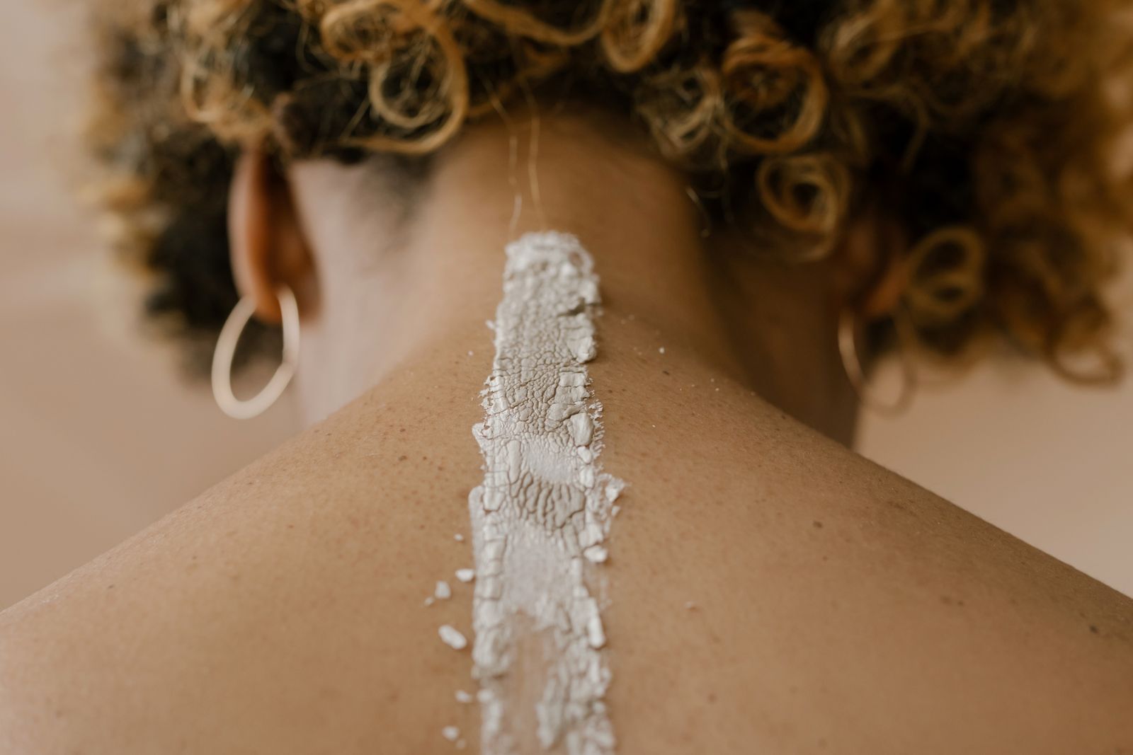 Inside the Moroccan Hammam Ritual at Kimantra: A Step-by-Step Photo Story 9 Pale mineral clay applied in a strip along the spine and neck, seen from behind