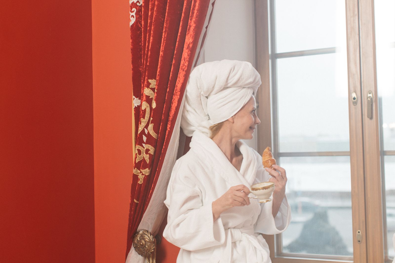 Inside the Moroccan Hammam Ritual at Kimantra: A Step-by-Step Photo Story 12 Woman in a white robe and hair towel sitting by a bright window with tea and a pastry